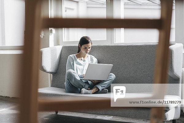 Yung Frau sitzend in ihrer neuen Wohnung mit einem Laptop