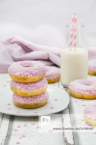Doughnuts mit rosa Puderzucker und einer Flasche Milch