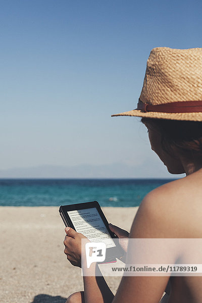 Griechenland  junge Frau am Strand liest E-Book