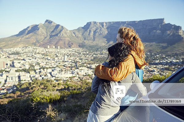 South Africa  Cape Town  Signal Hill  two young women leaning against car overlooking the city