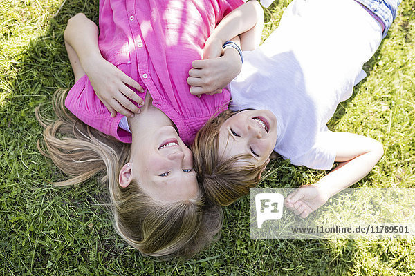 Zwei glückliche Schwestern auf der Wiese liegend