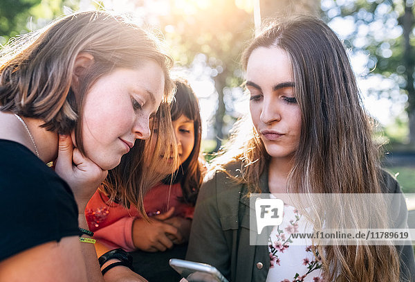Three girls using smartphone outdoors