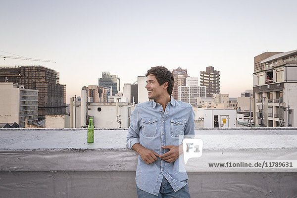 Confident young man standing on a rooftop terrace