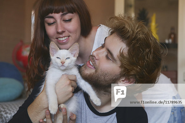 Junges Paar mit Kätzchen zu Hause