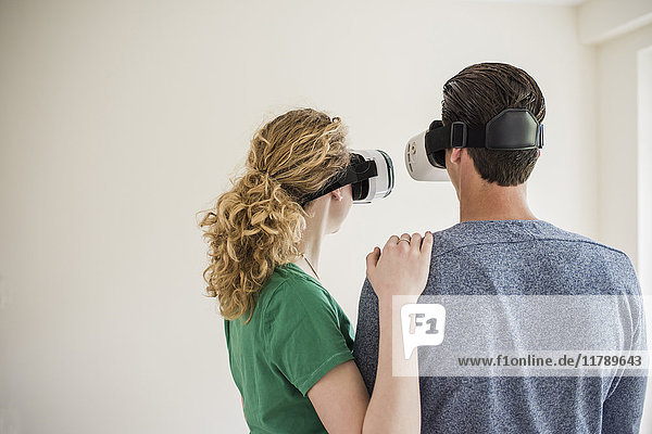 Young couple in empty apartment wearing VR glasses