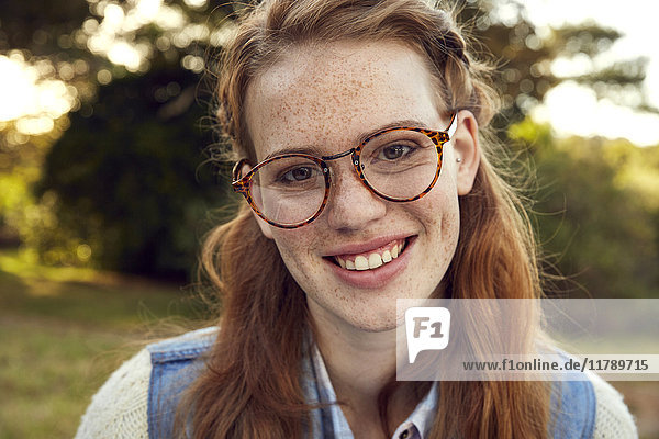Porträt der rothaarigen jungen Frau mit Sommersprossen und Brille