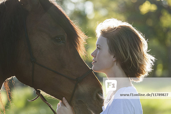 Profile von junger Frau und Pferd im Gegenlicht