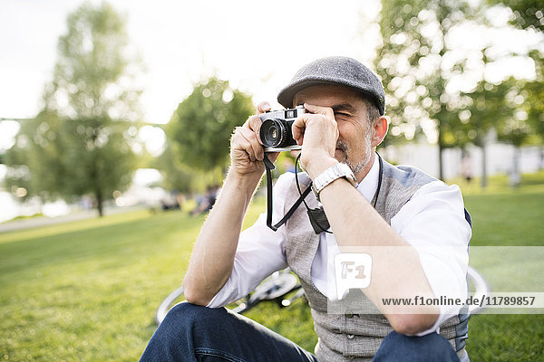 Mature businessman taking a picture with camera in park