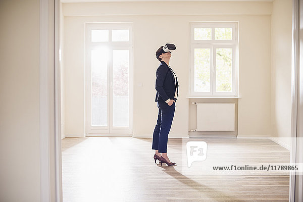 Frau in leerer Wohnung mit VR-Brille