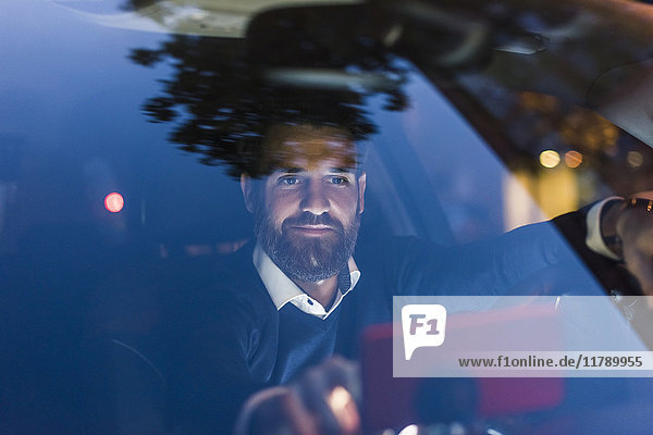 Businessman using navigation device in car at night
