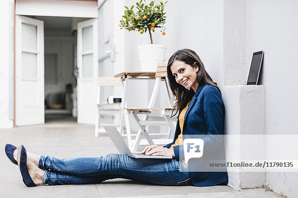 Lächelnde Geschäftsfrau mit Laptop auf dem Boden