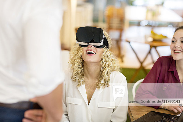 Blonde Frau beim Ausprobieren der VR-Brille in einer Werkstatt