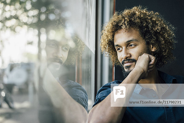Man with beard and curly hair looking out of window