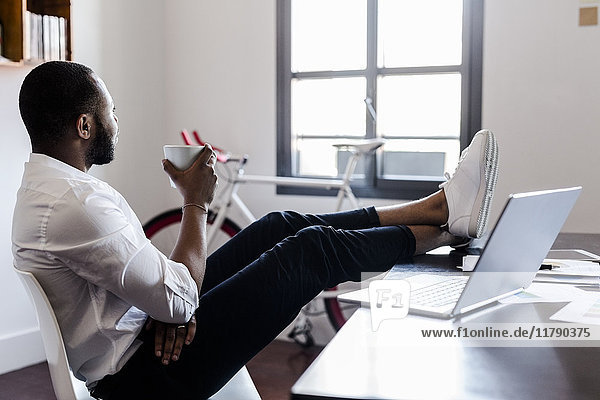 Entspannter Mann im Home-Office mit Füßen auf dem Schreibtisch