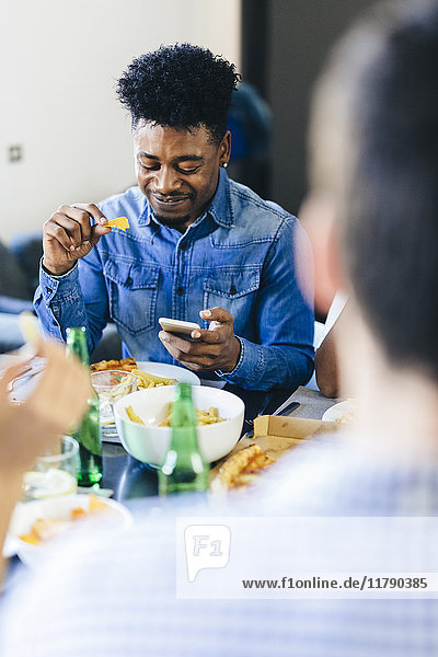 Smiling man looking at cell phone at dining table