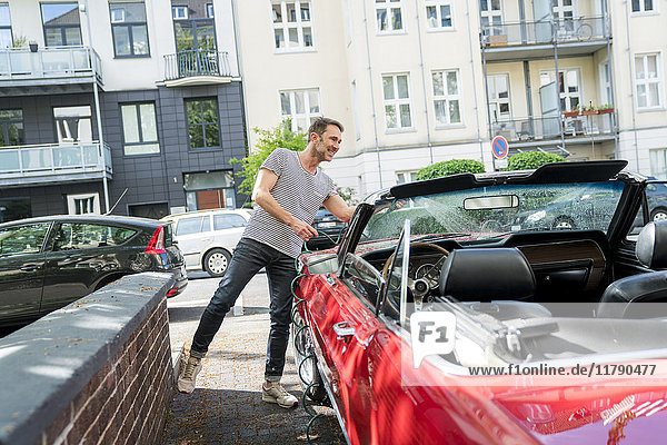 Smiling mature man washing his sports car
