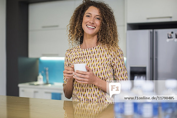 Porträt der lächelnden Frau in der Büroküche mit Tasse