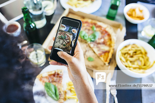 Handaufnahme Handyfoto von Pizza auf dem Tisch