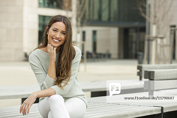 Junge Frau auf einer Bank sitzend  lächelnd