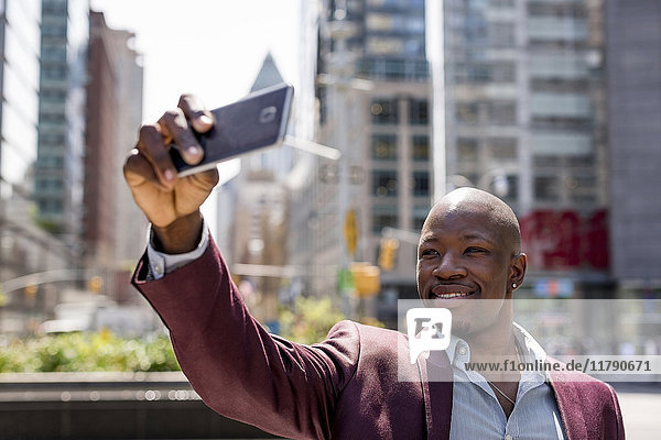 USA  New York City  Manhattan  stilvoller Geschäftsmann  der sich mit seinem Smartphone selbstständig macht.