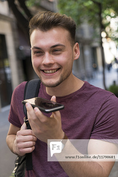 Glücklicher junger Mann mit Handy in der Stadt
