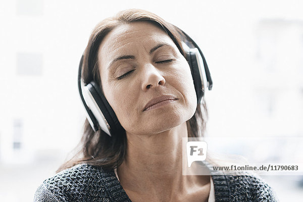 Portrait of woman with eyes closed listening music with headphones