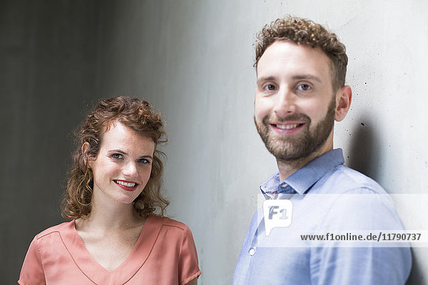 Portrait of smiling man and woman at concrete wall