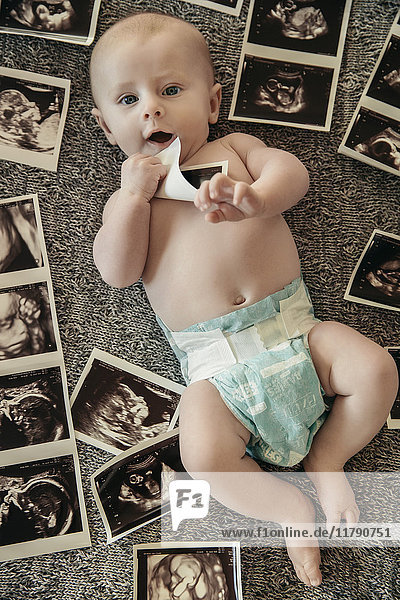 Baby auf einer Decke mit Ultraschallbildern von sich selbst