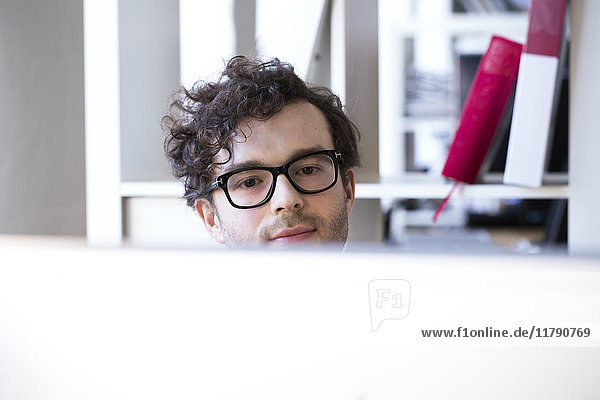 Zuversichtlicher Mann im Büro mit Blick auf den Computerbildschirm