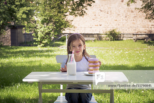 Girl with stack of donuts on garden table