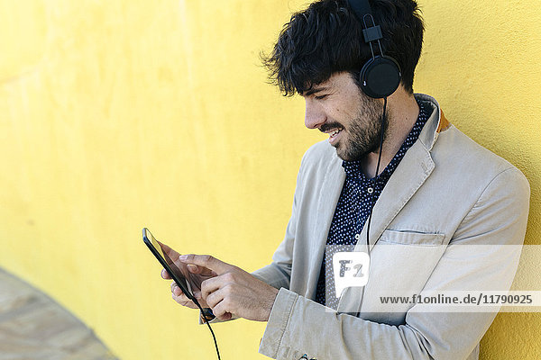 Lächelnder junger Mann mit Kopfhörer und Handy