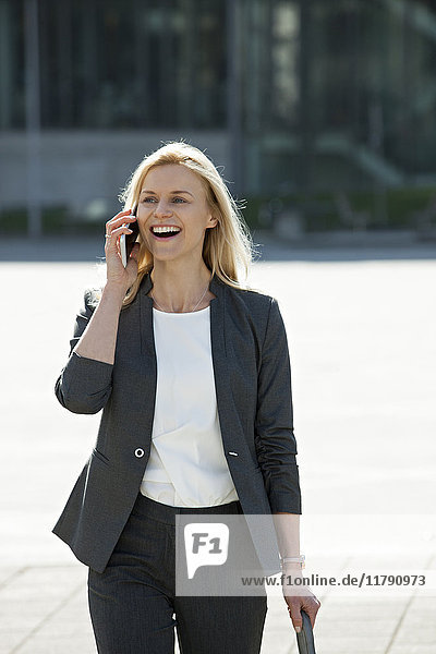 Porträt einer lachenden blonden Geschäftsfrau am Telefon