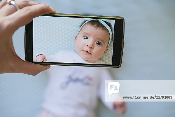 Woman taking a cell phone picture of a baby girl