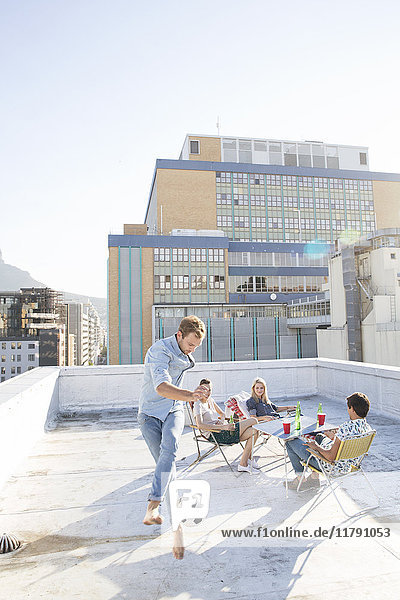 Friends meeting on rooftop terrace in summer  playing football