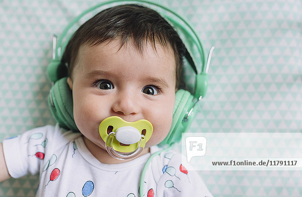 Portrait of baby girl with headphones and pacifier