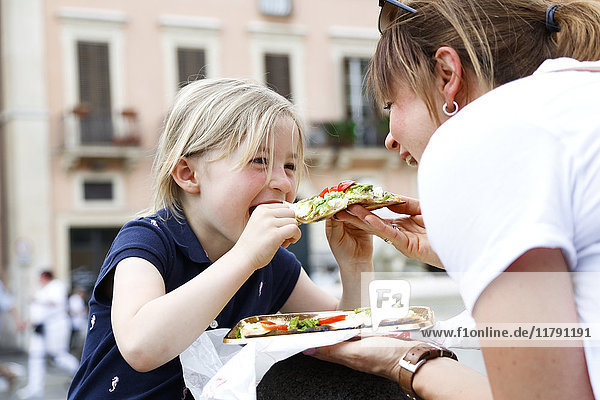 Italy  mother and little daughter eating Pizza together