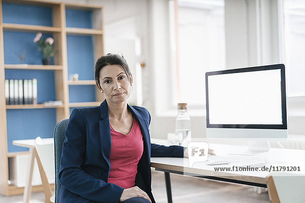 Portrait of serious businesswoman sitting at desk in a loft