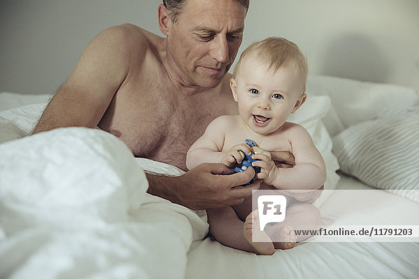Erwachsener Vater und Baby spielen im Bett