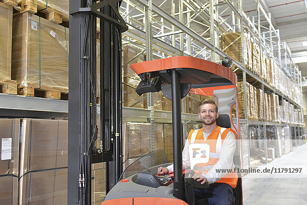 Portrait of smiling man in factory hall on forklift