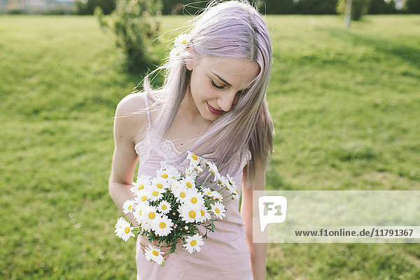 Lächelnde Frau mit Gänseblümchen auf einer Wiese