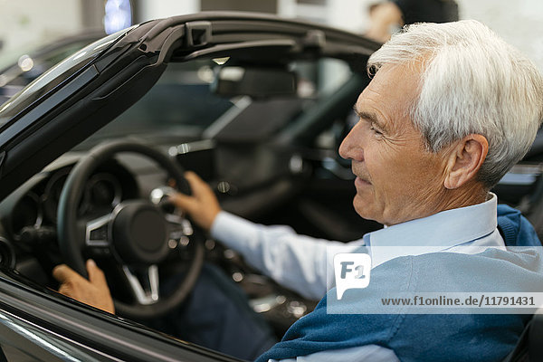 Senior man testing convertible in car dealership