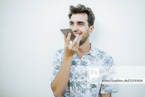 Man using cell phone in front of white wall