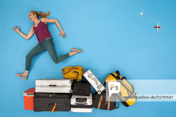 Happy woman jumping over luggage