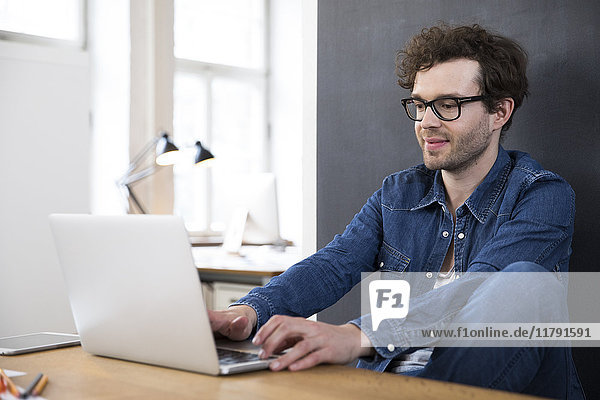 Lächelnder Mann mit Laptop im Büro