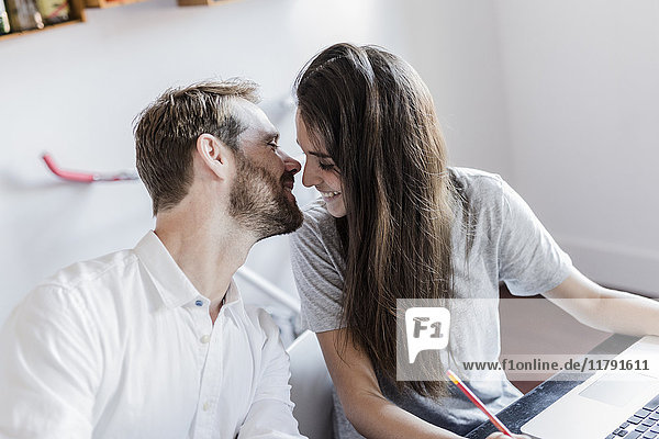 Happy couple with laptop at home kissing