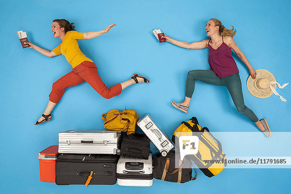 Friends jumping over luggage   looking happy