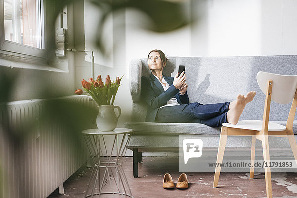 Businesswoman sitting on couch in a loft looking out of the window