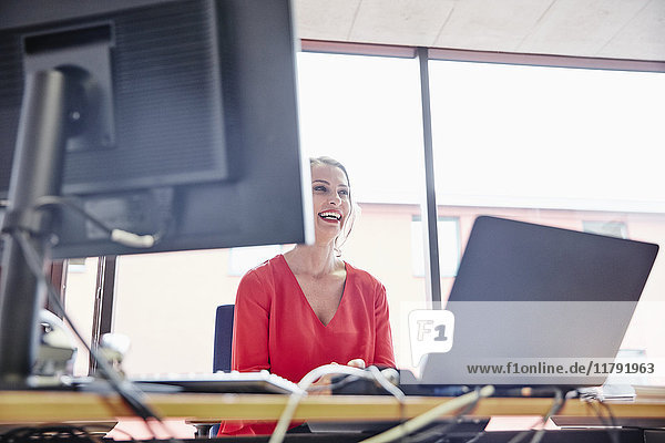Lachende Frau am Schreibtisch im Büro