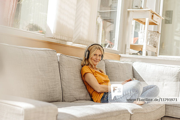 Woman at home sitting on couch wearing headphones