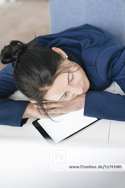 Überarbeitete Frau schläft auf Tablette im Büro